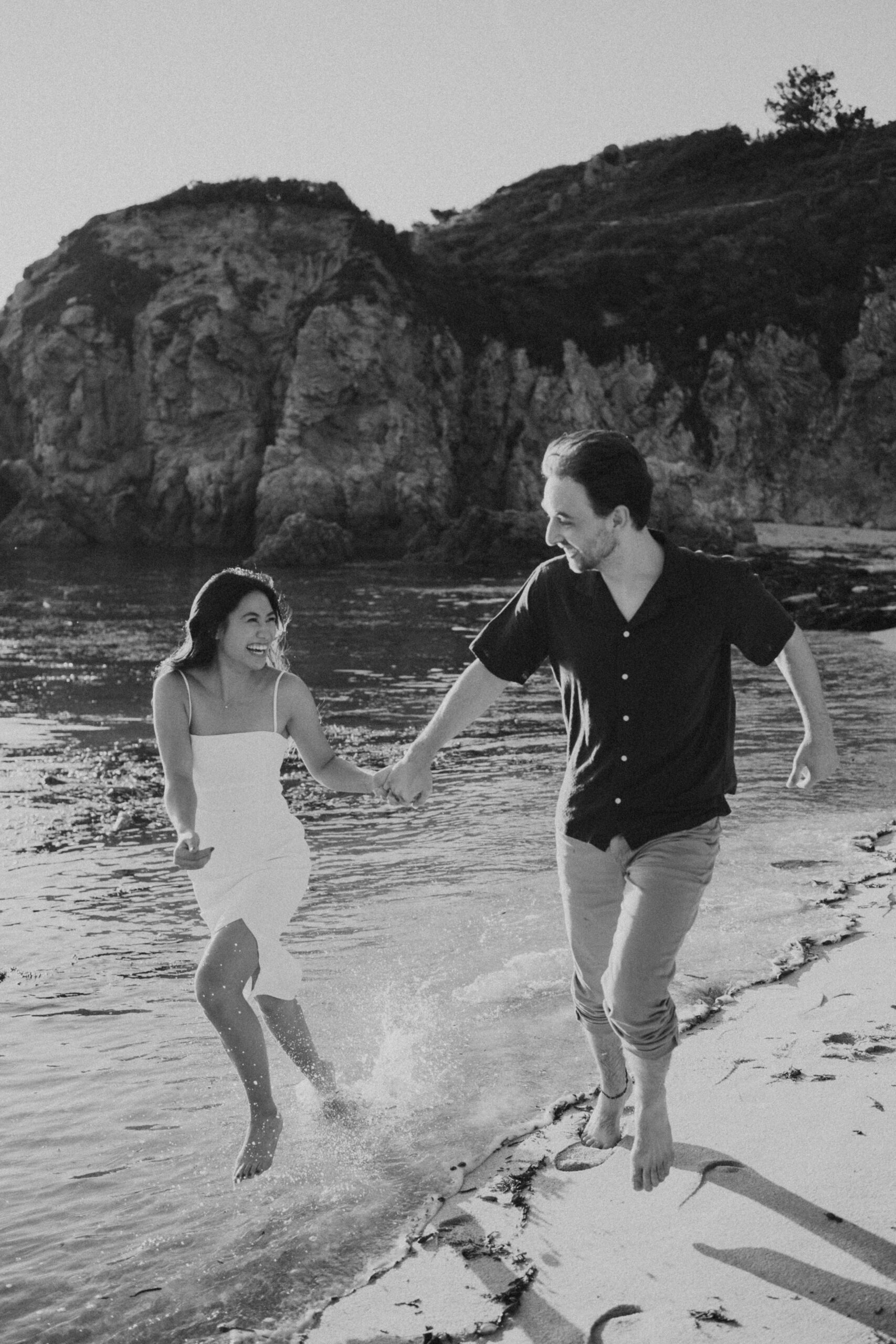 Fine art engagement portrait of R & E on the cliffs of Point Lobos, Carmel coastline — soft golden light and ocean backdrop.